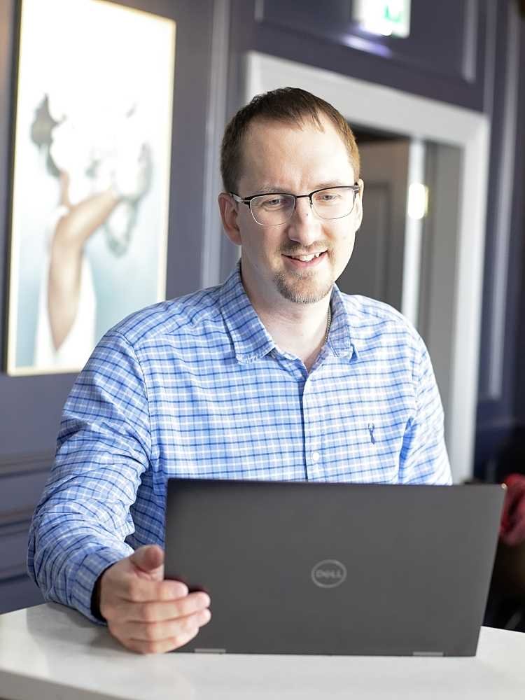 Mike working at his laptop with other people in the background